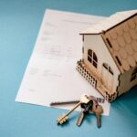 Miniature wooden house with keys and contract symbolizing real estate pro forma fail