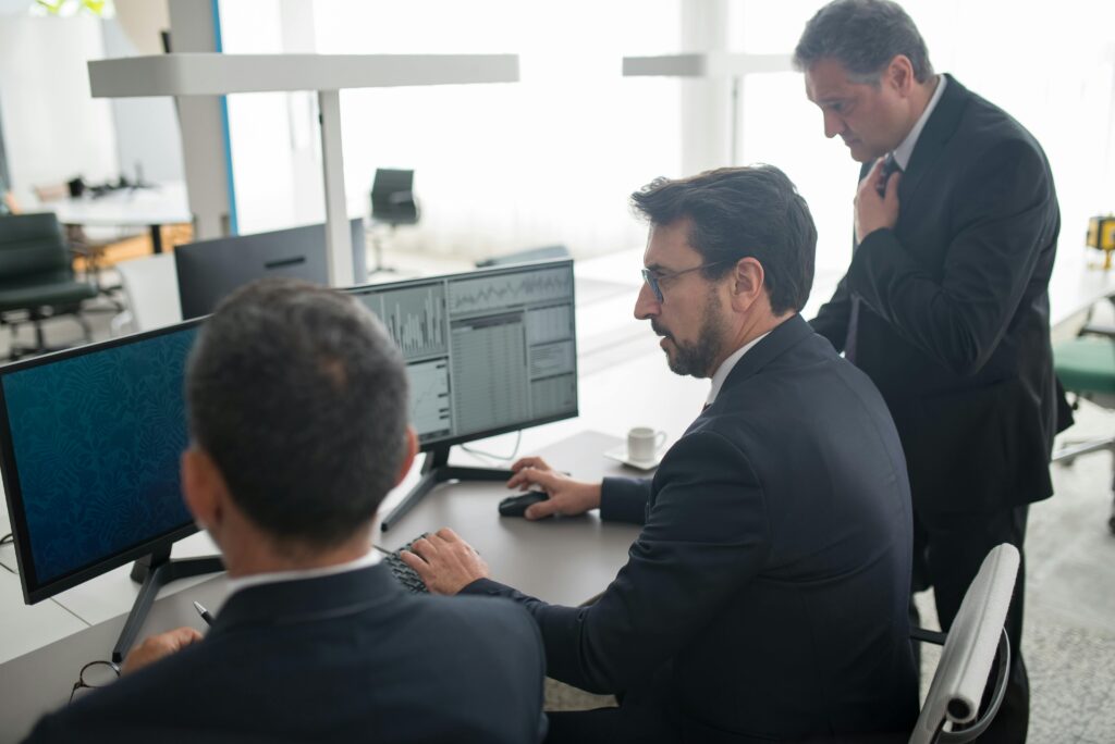 Colleagues in a modern office reviewing stock market trends and data on multiple screens for white-label prediction platform